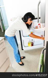 Black woman looking in fridge of modern kitchen interior