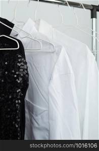 black women&rsquo;s blouse with red sequins, white men&rsquo;s shirts hang on a white iron hanger, sale concept