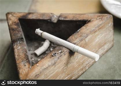 Black wood ashtray with cigarette stubs in closeup