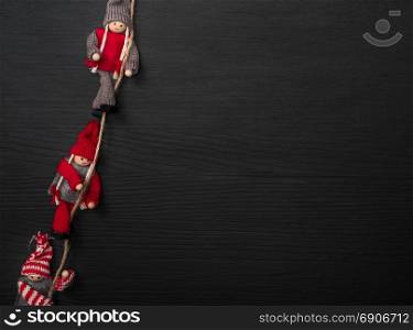 black wooden background with wooden puppets on a rope, empty space on the right