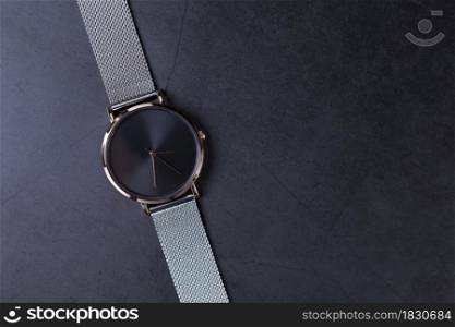Black wrist watch for women with metal strap top view on gray background.