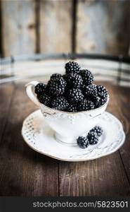 Blackberries in a mug on wooden background