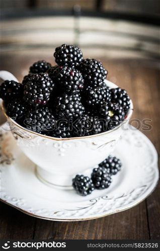 Blackberries in a mug on wooden background
