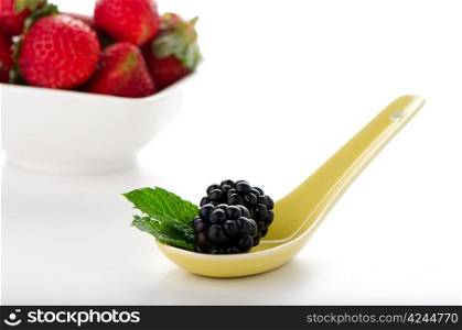 Blackberries in ceramic spoon on white background.
