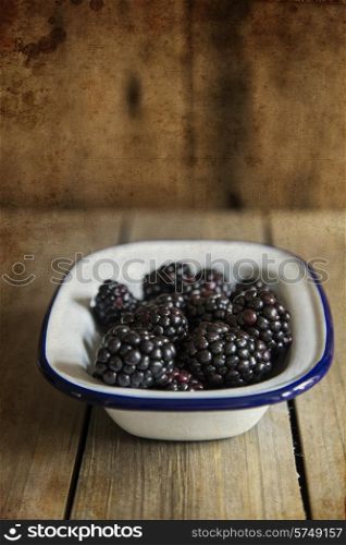 Blackberries in rustic setting with wooden background with added texture filter