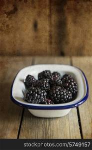 Blackberries in rustic setting with wooden background with added texture filter