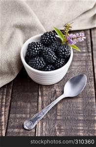 Blackberry in white bowl and spoon on grunge wooden board. Natural healthy food.Still life photography