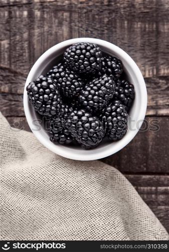 Blackberry in white bowl on grunge wooden board. Natural healthy food.Still life photography