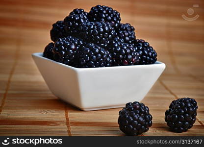 blackberry in white ceramic bowl on wooden background