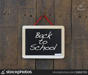 Blackboard hanging on a old wooden wall with Back to school.