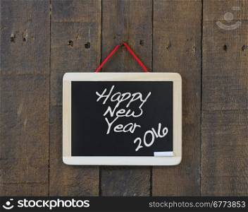 Blackboard hanging on a old wooden wall with Happy New Year.