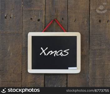 Blackboard hanging on a old wooden wall with Merry Christmas.