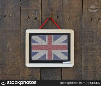 Blackboard hanging on a old wooden wall with UK flag.