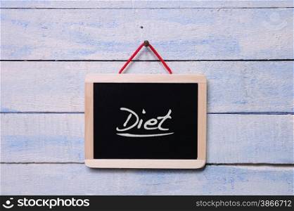 Blackboard hanging on a old wooden wall with word, Diet.