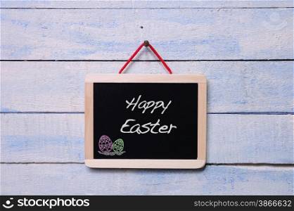 Blackboard hanging on a old wooden wall with word Happy Easter.