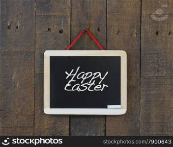 Blackboard hanging on a old wooden wall with word Happy Easter.