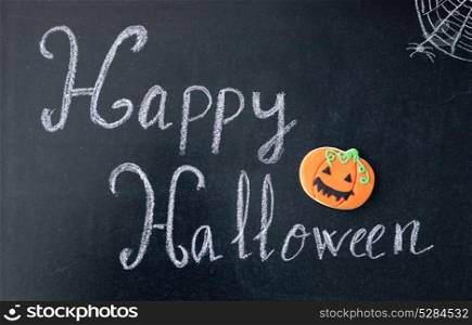 "Blackboard with the words "Happy Halloween" and a pumpkin cookie"