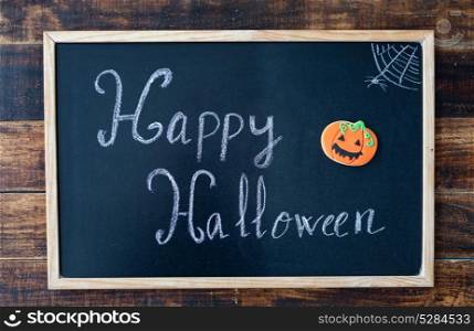 "Blackboard with the words "Happy Halloween" and a pumpkin cookie"