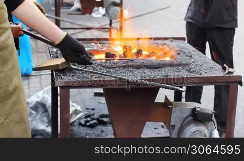 blacksmith corrects coal on fire where heated details