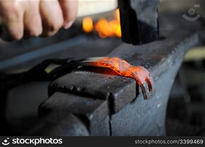 Blacksmith forges a hot spear on the iron anvil