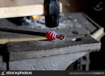 Blacksmith forges a red-hot iron in the forge