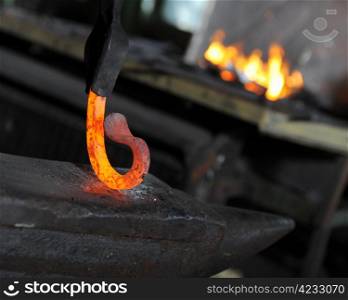 Blacksmith forges a red-hot iron in the forge