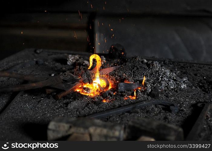blacksmith heats a decorative piece in the forge