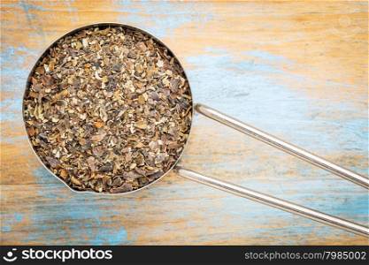bladderwrack seaweed flakes - top view of a metal measuring scoop against painted wood
