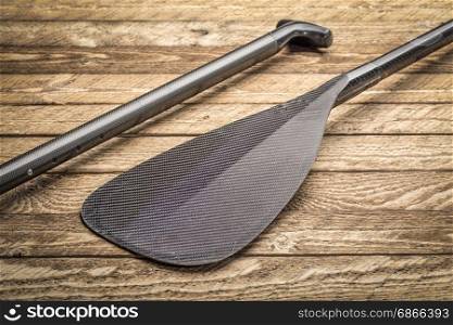 blade and grip of carbon fiber canoe or SUP (stand up paddleboard) paddle against weathered wood background