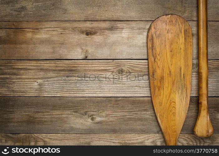 blade and grip of wooden canoe paddle against rust wood background with a copy space