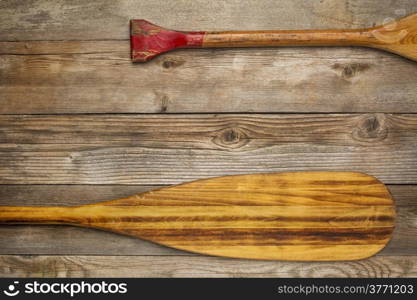 blade and grip of wooden canoe paddle against rustic wood background with a copy space