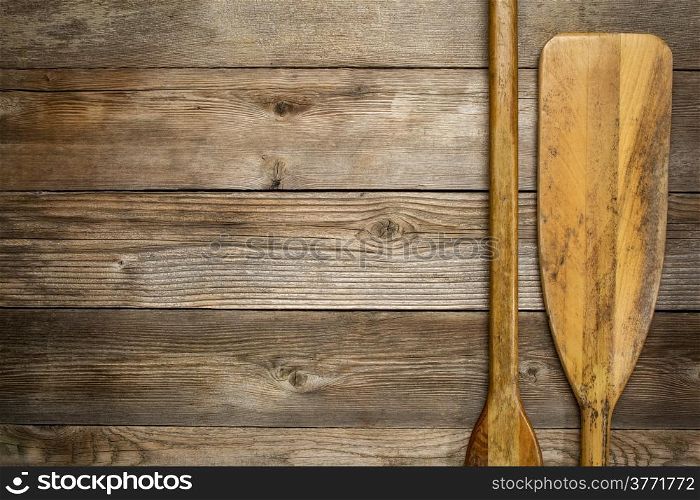 blade and grip of wooden canoe paddle against rustic wood background with a copy space