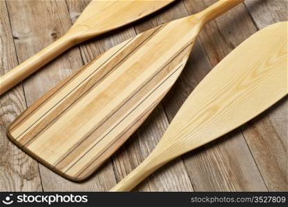 blades of three wooden canoe paddles of different shape against grunge wood surface