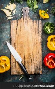 Blank aged wooden cutting board with kitchen knife and Bell colorful paprika peppers , top view