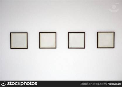 Blank black picture frame template for place image or text inside on the white wall in a row close-up. Blank black picture frame template for place image or text inside on the white wall in a row