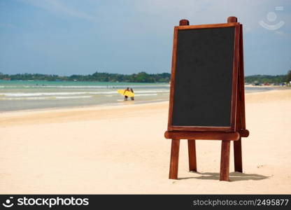 Blank black wooden chalkboard stand in sand on tropical beach