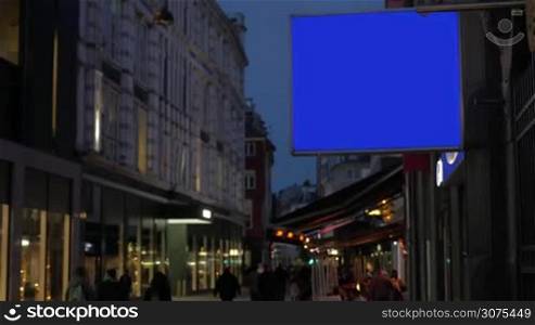 Blank blue screen banner for advertising hanging on the building in night city street