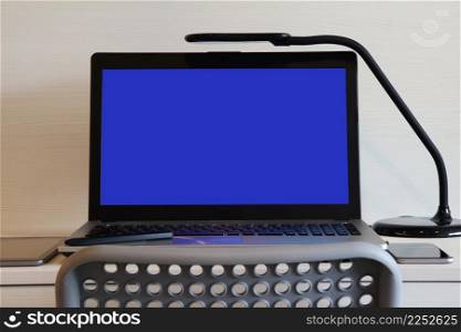 blank blue screen laptop computer with table lamp is on twooden desk as workplace concept