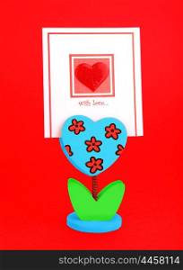 Blank card with red heart &amp; flower holder isolated on red background, conceptual image of love &amp; Valentine&rsquo;s day holiday