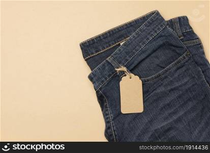blank cardboard rectangular tag tied to blue jeans. Top view, copy space
