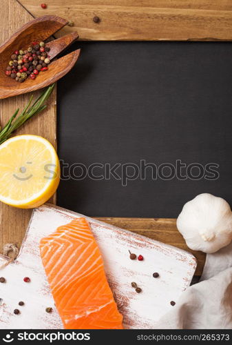 Blank chalkboard for text. With raw seafood and vegetables and spices on stone background