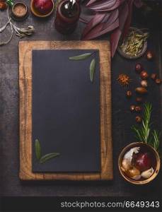 Blank chalkboard in wooden frame and cooking ingredients on dark kitchen table background, top view, frame .
