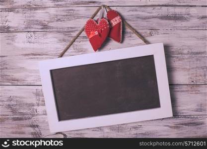 Blank chalkboard on the shabby white background and red hearts for Valentine day greetings