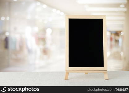 Blank chalkboard standing on sack tablecloth over blur store with bokeh background, space for text, mock up, product display montage
