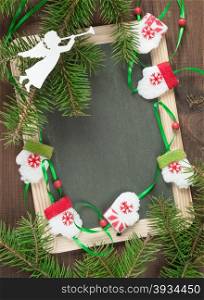 Blank chalkboard surrounded by green fir branches, doll mittens and white felts angel