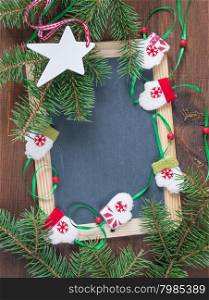 Blank chalkboard surrounded by green fir branches, doll mittens and white wooden star