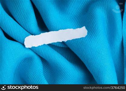 Blank copy space scrap of paper on blue background cloth wavy folds of textile texture design of elegant material