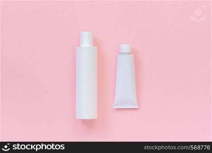 Blank cosmetic or medical white plastic bottle and tin tube for cream, shampoo, ointment, toothpaste or other product on pink background. Template or Mock up for your design. Copy space Top view.. Blank cosmetic or medical white plastic bottle and tin tube for cream, shampoo, ointment, toothpaste or other product on pink background. Template or Mock up for your design. Copy space Top view
