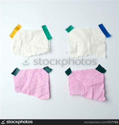 blank crumpled sheets of paper glued with rubber colored adhesive tape on a white background, copy space
