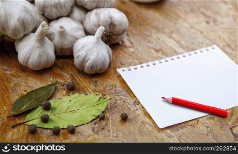 blank for recipe or note with pensil on wooden surface with garlic and spices